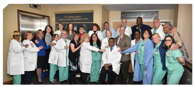 Linwood Haith Jr., M.D., seated at center, and members of the Nathan Speare Regional Burn Treatment Center team gather for a team photo outside of the burn center entrance at Crozer-Chester Medical Center.    